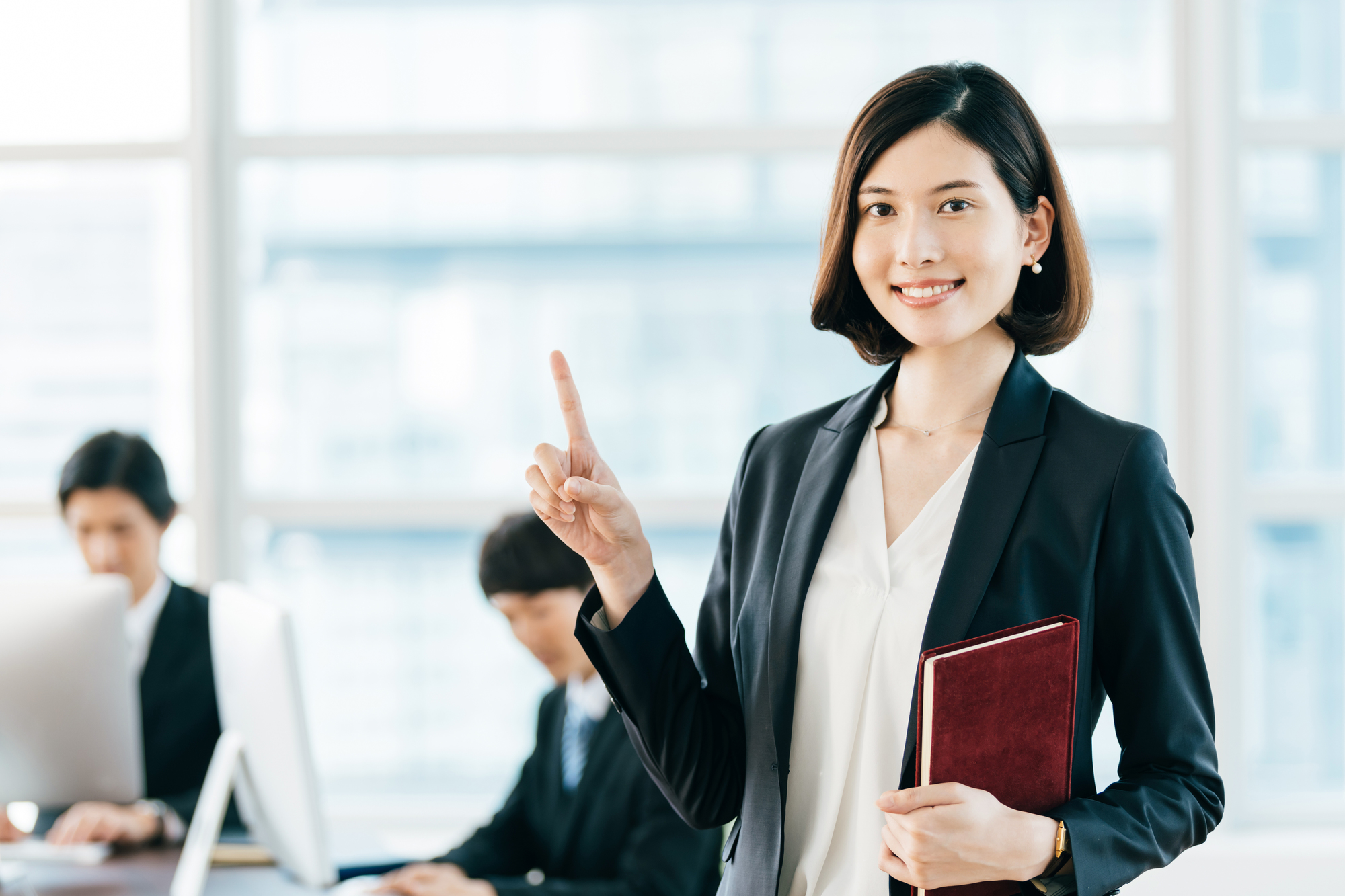オフィスで人差し指を立てて笑顔を向けてくる女性