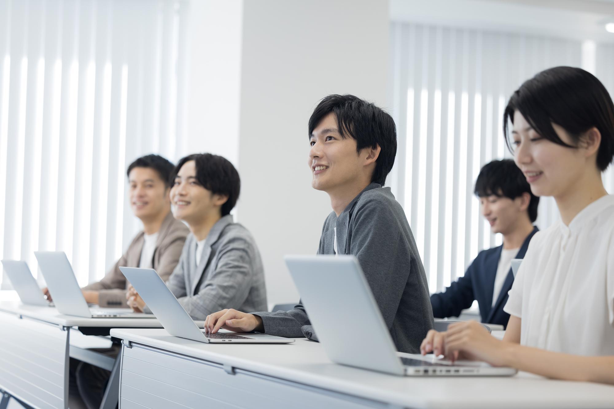 セミナールームで開催される研修を、各自ノートPC持参で受講するビジネスパーソンのチーム